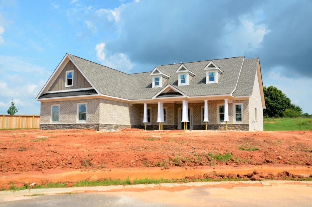 Current image: Brick modern family home under bright sky, showcasing new construction and architectural style.